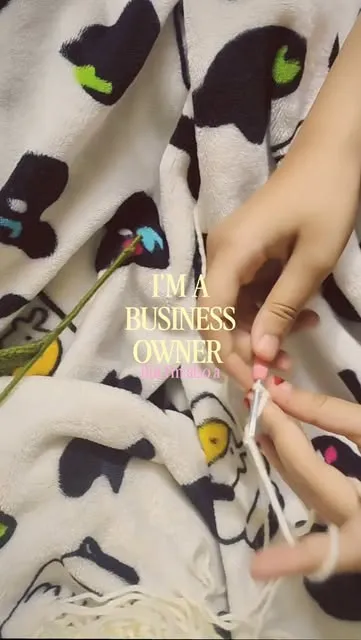 Hands crocheting with a hook and white yarn